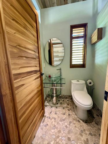 a bathroom with a toilet and a wooden door at hotelsonidosamados-osa in Sierpe