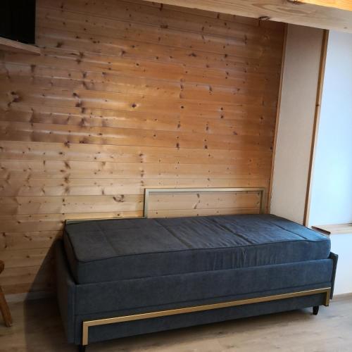 a bed in a room with a wooden wall at Hotel Gran Baita in Gressoney-Saint-Jean