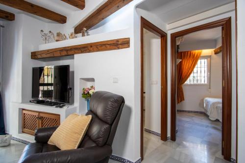 een woonkamer met een leren stoel en een televisie bij Aldea del Mar Buganvilla Apartament in Torrevieja