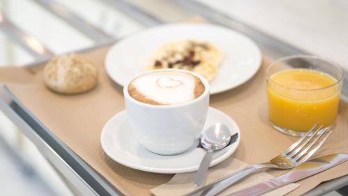a table with a cup of coffee and a plate of food at Holiday Inn Express Molins de Rei by IHG in Molins de Rei