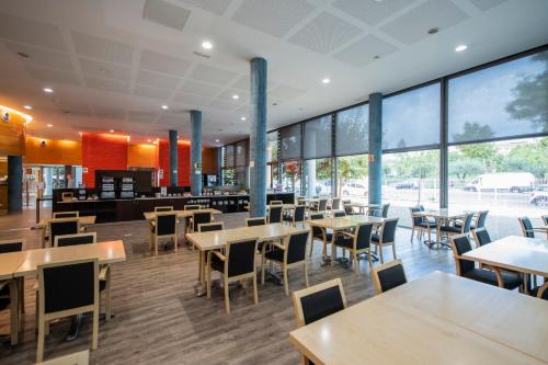 a restaurant with tables and chairs and large windows at Holiday Inn Express Molins de Rei by IHG in Molins de Rei