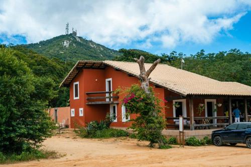 a red house with a mountain in the background at EcoPousada Pico do Jabre in Matureia