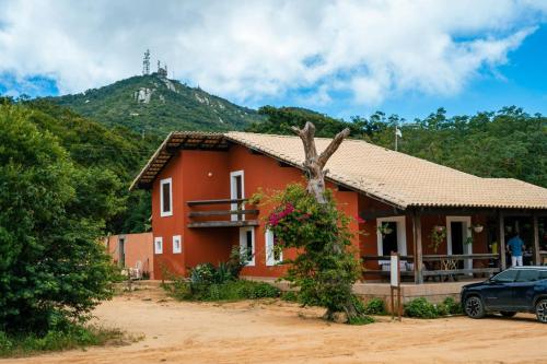 ein rotes Haus mit einem Berg im Hintergrund in der Unterkunft EcoPousada Pico do Jabre in Matureia