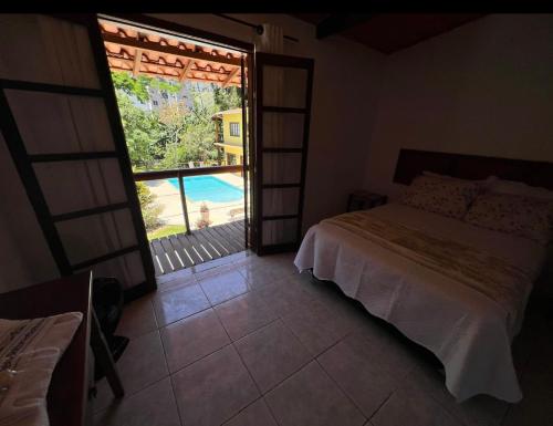 a bedroom with a bed and a view of a pool at Villa Aconchego Corrêas Itaipava in Petrópolis