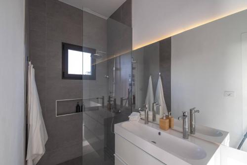 y baño blanco con lavabo y ducha. en Finca Las Huellas - Moderno apartamento con vistas al mar y al volcán, en Los Llanos de Aridane