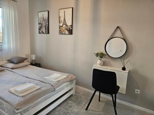 1 dormitorio con 1 cama con espejo y silla en Apartament - Osiedle Przylesie en Namysłów