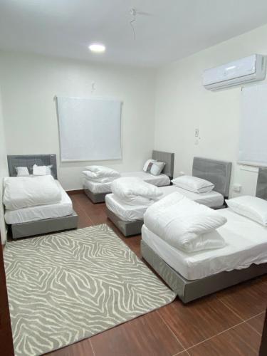 a room with four beds and a white wall at Alfatih apartments شقة الفتح in Al Madinah