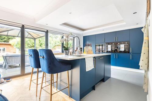 une cuisine avec des placards bleus et des tabourets de bar bleus dans l'établissement Gorgeous House in Sidcup, à Streatham Hill