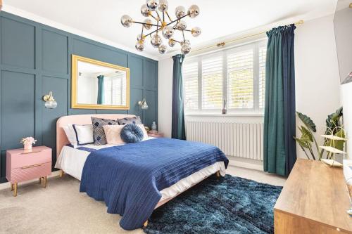 a bedroom with a bed with blue walls and a chandelier at Gorgeous House in Sidcup in Streatham Hill