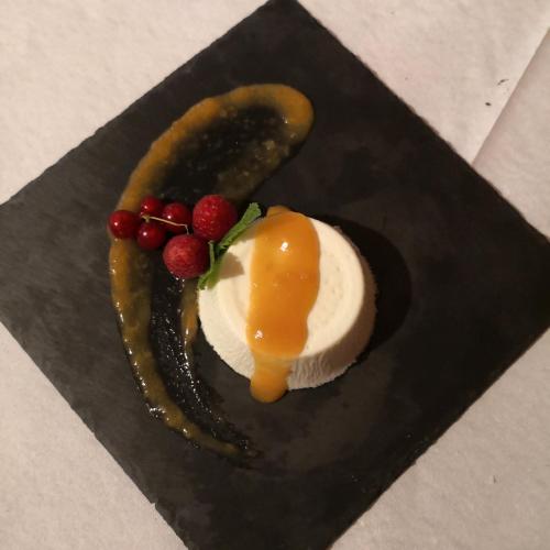 a dessert with fruit and a letter s on a black plate at Hotel Gran Baita in Gressoney-Saint-Jean