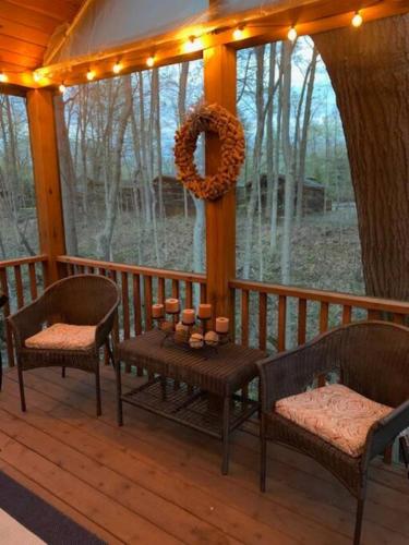 a porch with two chairs and a wreath and candles at Knotty but Nice-sleeps 6-one minute to lake! in Three Oaks