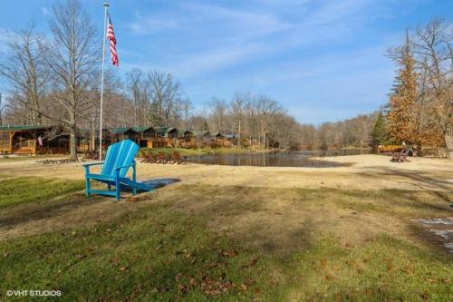 a blue chair sitting in the grass next to a lake at Knotty but Nice-sleeps 6-one minute to lake! in Three Oaks