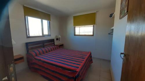 a bedroom with a bed with a red and blue striped blanket at La Chakana in Uspallata