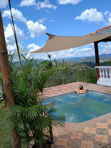 a man laying in a swimming pool with a umbrella at Finca con vista al embalse y jacuzzi in Guatapé