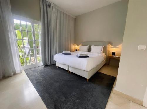 - une chambre avec un lit blanc et une grande fenêtre dans l'établissement 4 bedroom Villa in Top location - Heating Pool, à Marbella