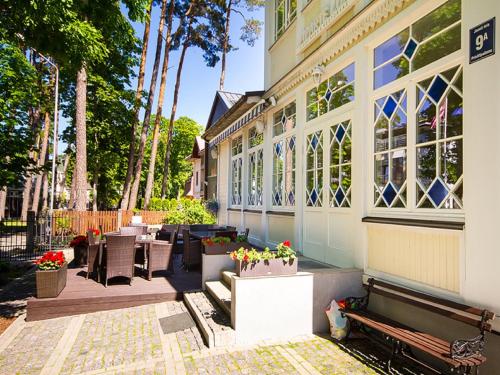 a building with tables and chairs and flowers in pots at Aparte Lux Jurmala in Jūrmala