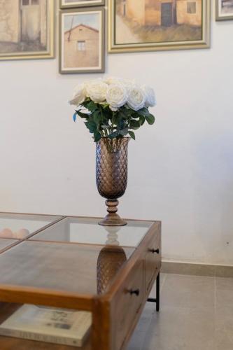 a vase with white roses sitting on a glass table at Family Little Paradise in Ružić