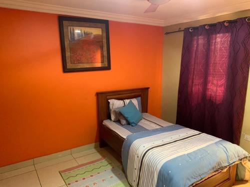 - une chambre avec des murs orange et un lit avec un oreiller bleu dans l'établissement Apartment For Short and Long Stay, à Accra