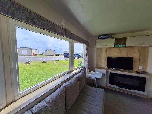 a living room with a couch and a large window at 3 Bedroom Deluxe Caravan at Haven Devon Cliffs in Exmouth