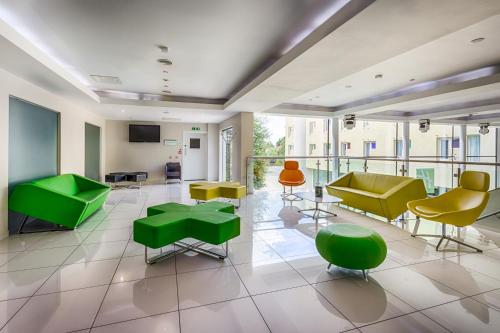 a lobby with green and yellow chairs and tables at Holiday Inn Sittingbourne, an IHG Hotel in Sittingbourne