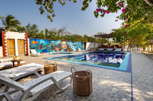 una piscina con sillas blancas y un mural en Marazao Beach Hotel & Spa en Tierra Bomba