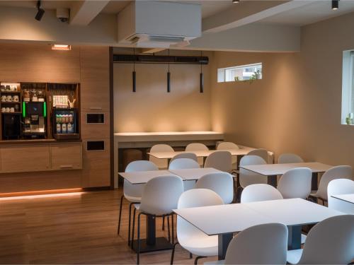 une salle à manger avec des tables et des chaises blanches dans l'établissement B&B HOTEL Vejle, à Vejle