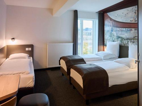 a hotel room with two beds and a window at B&B HOTEL Vejle in Vejle