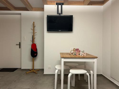Habitación con mesa y TV en la pared. en Wohnung am Postweg, en Netstal
