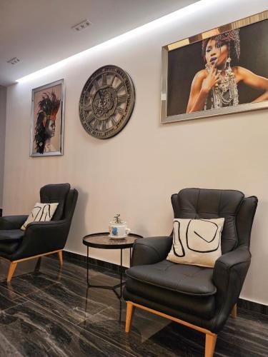 a living room with two chairs and a clock on the wall at 4 Stinët in Valbonë