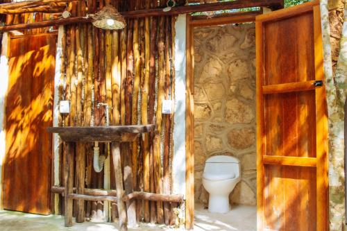 a bathroom with a toilet and a wooden wall at Selvaluna cabaña eco-chic in Tulum