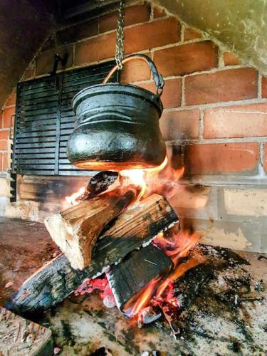 a pot hanging over a fire in a brick oven at 7Pines Bijambare - Air Spa in Sarajevo
