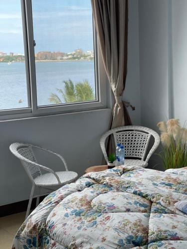 - une chambre avec un lit, deux chaises et une fenêtre dans l'établissement Arrabella Ocean View Home, à Dar es Salaam