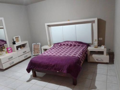 a bedroom with a purple bed and two white dressers at Casa muy espaciosa y cómoda in Delicias