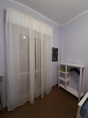 Zimmer mit einem Fenster mit weißen Vorhängen und einem Tisch in der Unterkunft Il Cortile in Brugherio
