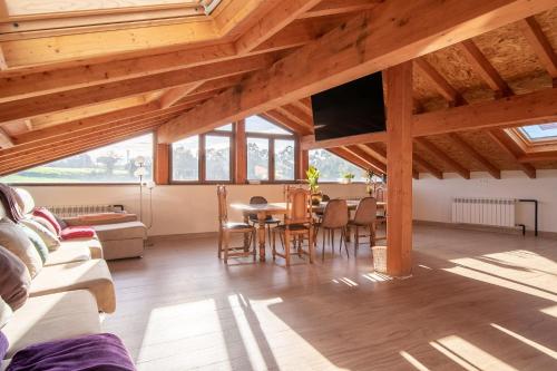 sala de estar con techos de madera, mesa y sillas en Casa Garabeto, en Luanco