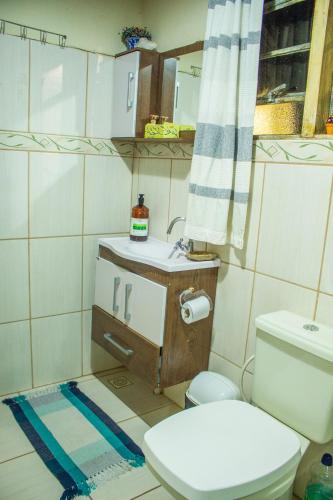 a bathroom with a toilet and a sink at CHALÉ ADOBE in Carrancas