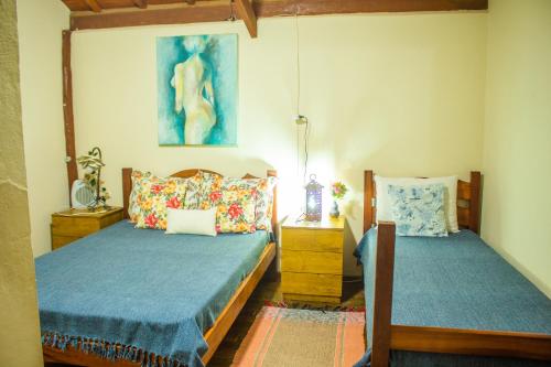 a bedroom with two beds and a painting on the wall at CHALÉ ADOBE in Carrancas