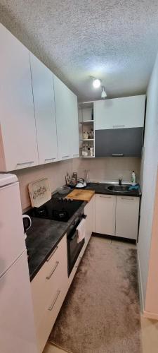 a kitchen with white cabinets and a black counter top at 7Pines Bijambare - Air Spa in Sarajevo