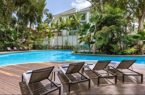 a table and chairs next to a swimming pool at Palm Cove Beachside Apartments - Sea and Mountain Views in Palm Cove