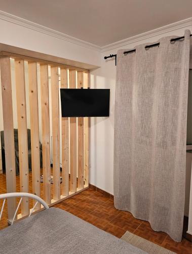 a room with a tv and a wall with a curtain at Casa d´Avó in Fiais da Telha