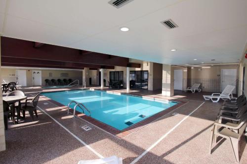 a swimming pool in a building with a table and chairs at Country Inn & Suites by Radisson, Council Bluffs, IA in Council Bluffs
