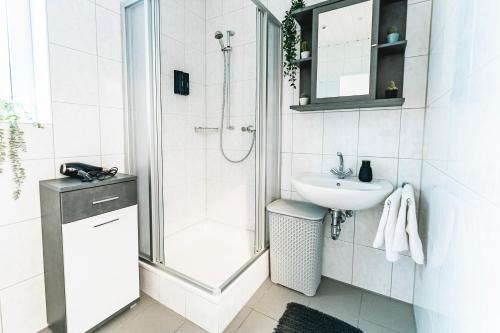 La salle de bains blanche est pourvue d'une douche et d'un lavabo. dans l'établissement Zentral-Kingsize Bett-Playstation 4-HBF nach Köln und Düsseldorf, à Haan