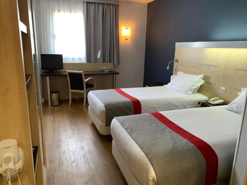 a hotel room with two beds and a desk at Holiday Inn Express Vitoria by IHG in Vitoria-Gasteiz