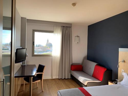 ビトリア・ガステイスにあるホリデイ イン エクスプレス ヴィトーリアのベッド、ソファ、デスクが備わるホテルルームです。