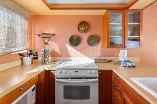 cocina con paredes de color naranja y estufa blanca en Bamboo Suite located across from the beach, 1 Bedroom sleeps 4, en Kihei