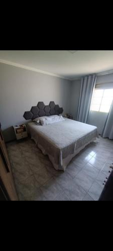 a bedroom with a large bed with a window at Casa completa in Marília