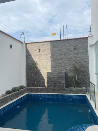 una piscina frente a un edificio con una pared de ladrillo en Alquiler de Casa / Chilca-Lima, en Salinas