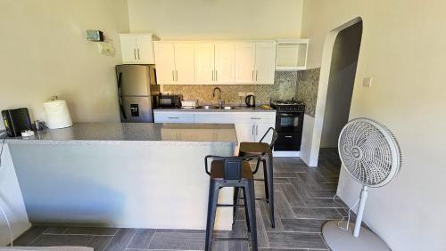 a kitchen with white cabinets and a counter with stools at Ihola's Nest in Craighton