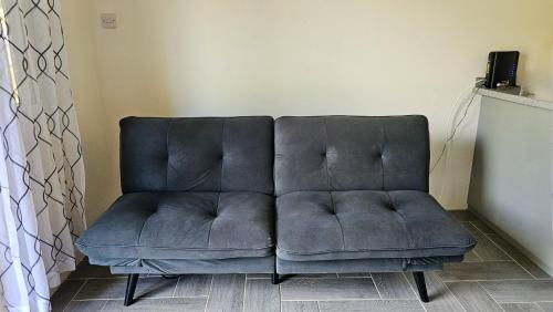 eine blaue Couch im Wohnzimmer in der Unterkunft Ihola's Nest in Craighton