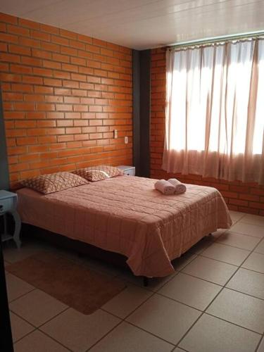 um quarto com uma cama numa parede de tijolos em Casa Tia Dori em Rio Forcação